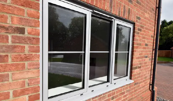 External view of a light grey Cortizo aluminium window with central bars, installed by Site Fix Fenestration Ltd.